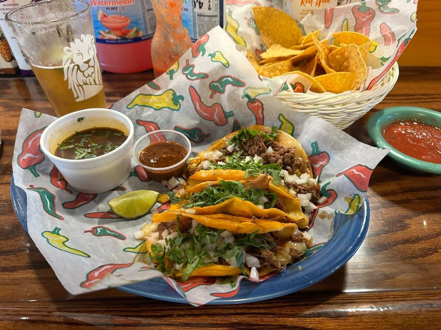 Taco plate with salsa, guacamole, chips, and drinks on a restaurant table