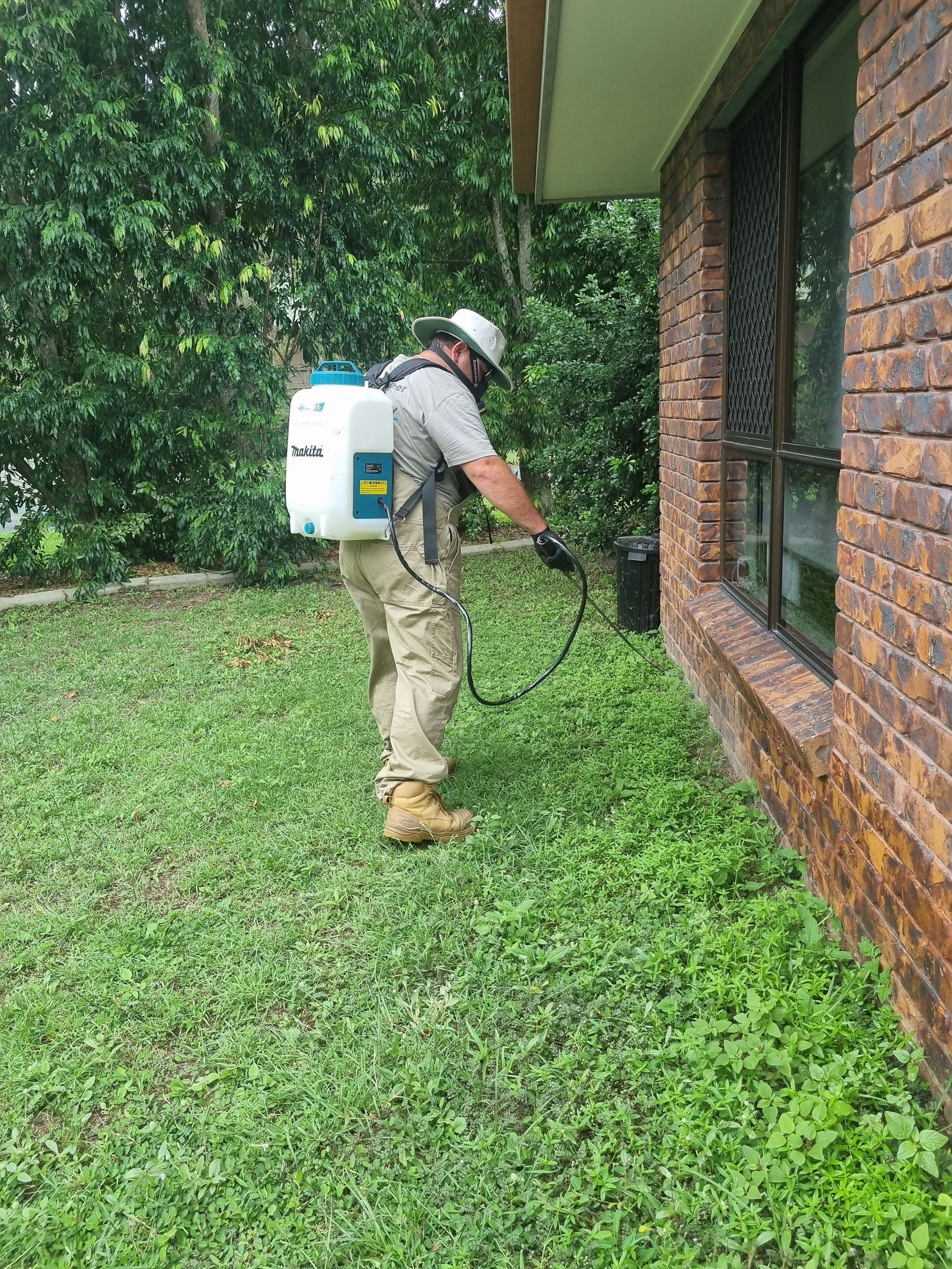 A Man in a Protective Suit is Spraying a Room With a Sprayer — Pioneer Pest Mackay In Glenella, QLD