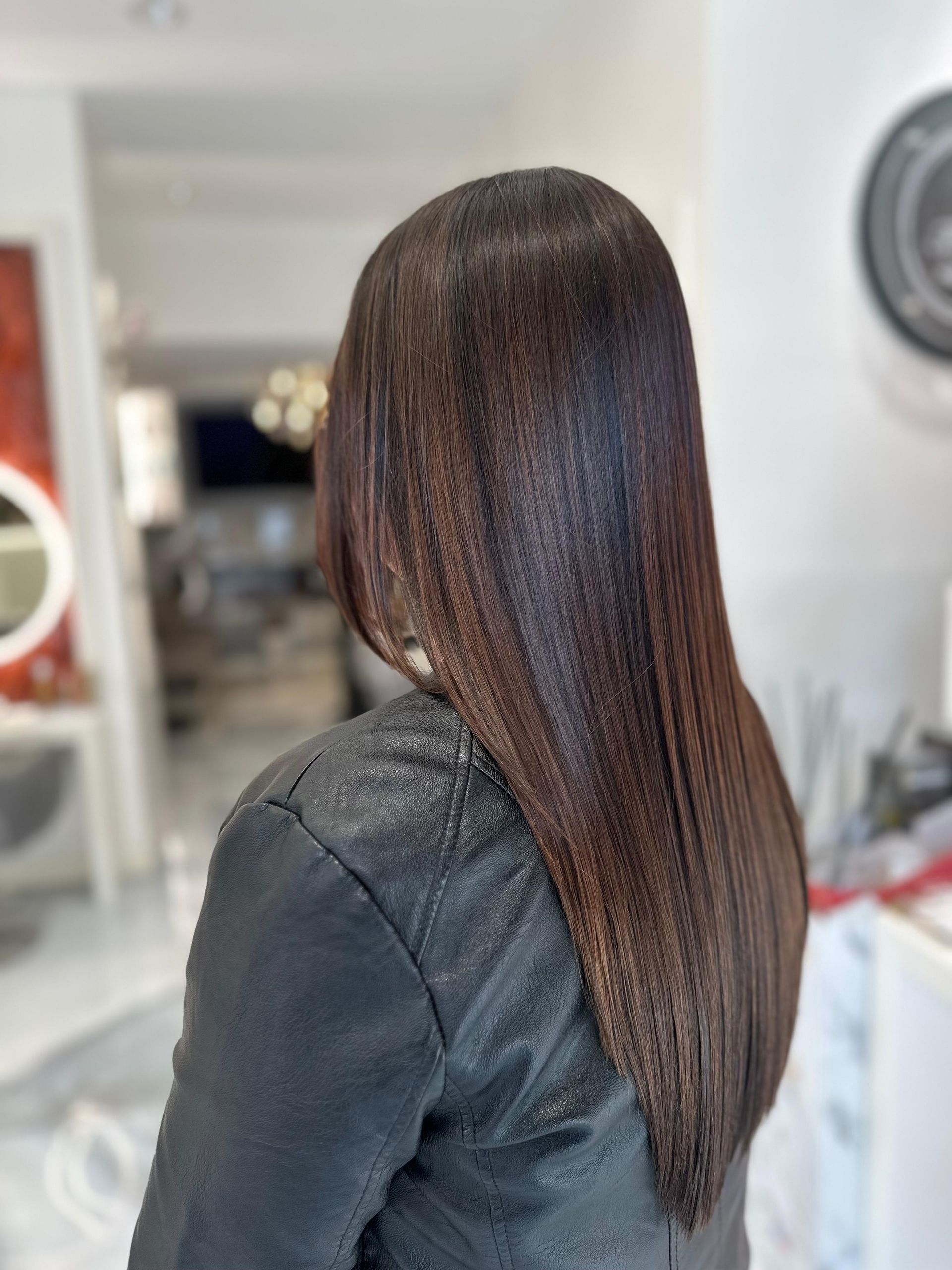 Donna con capelli scuri e lisci, che indossa una giacca nera, all'interno di un salone.
