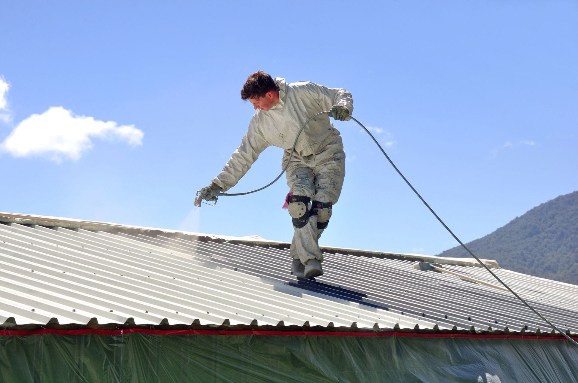 A man is spraying paint on the roof of a building
