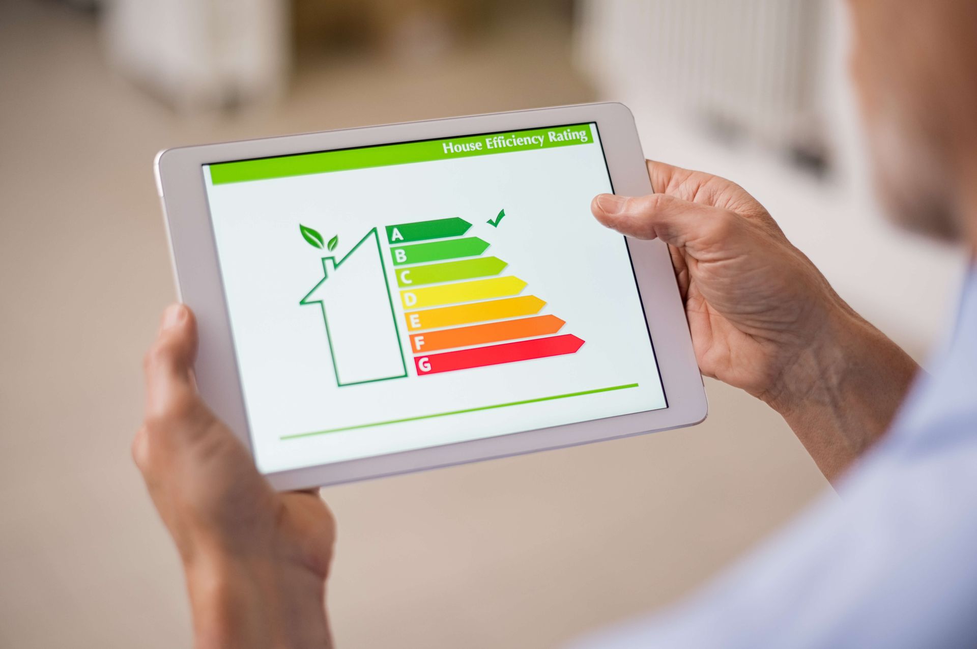 Une personne tient une tablette avec un tableau d'efficacité énergétique dessus