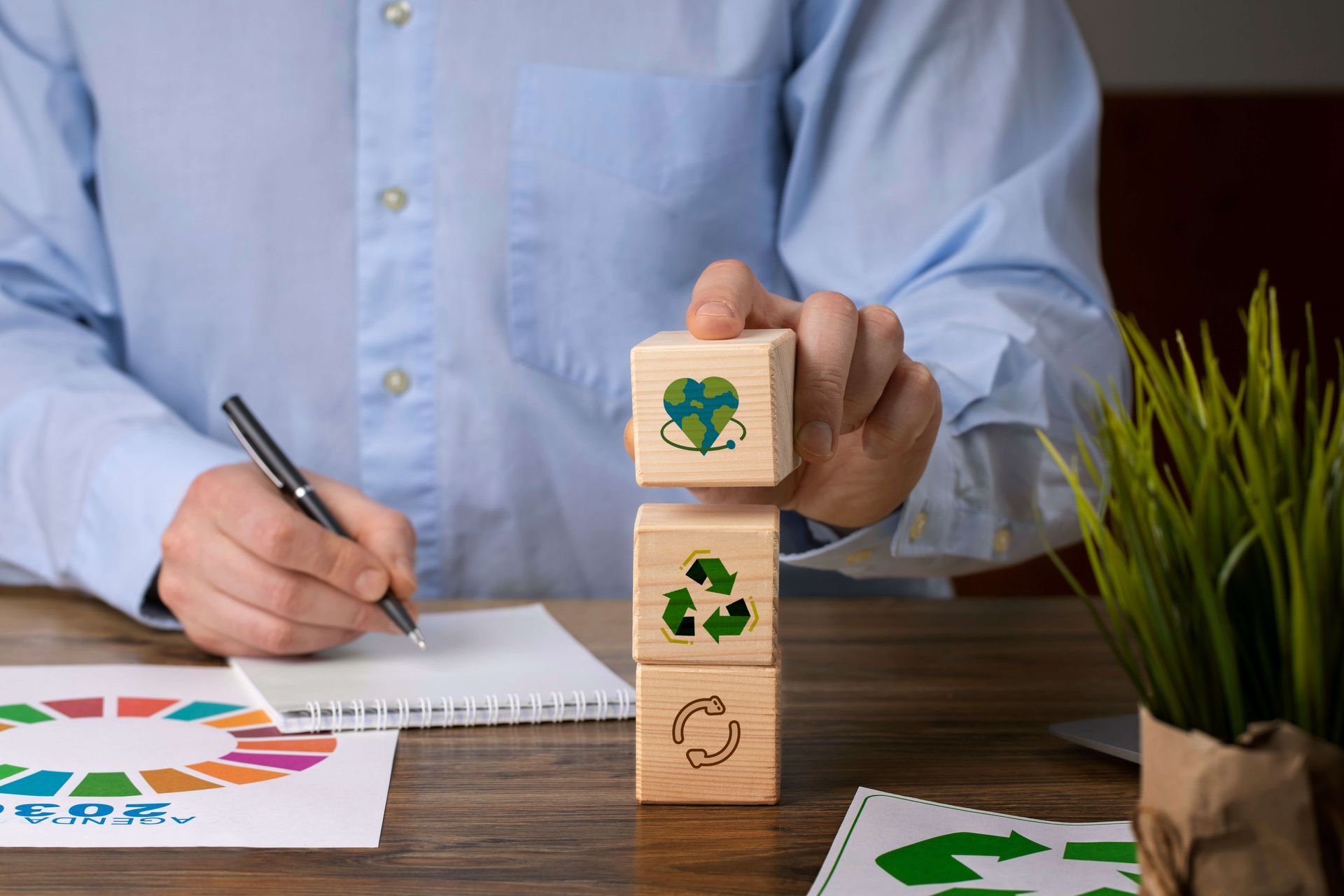 Un homme empile des blocs de bois portant des symboles de recyclage.