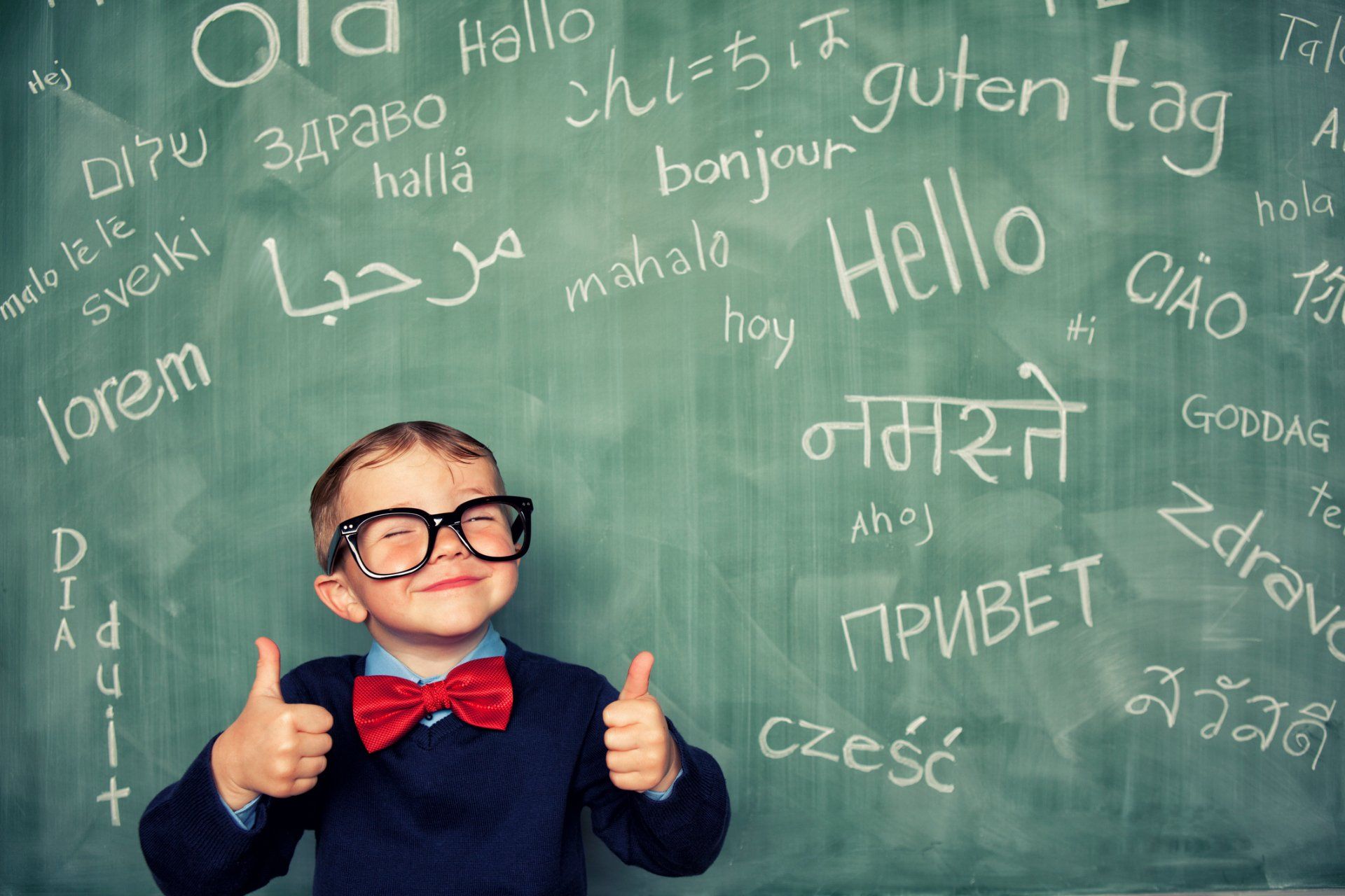 bambino davanti lavagna con espressioni in inglese