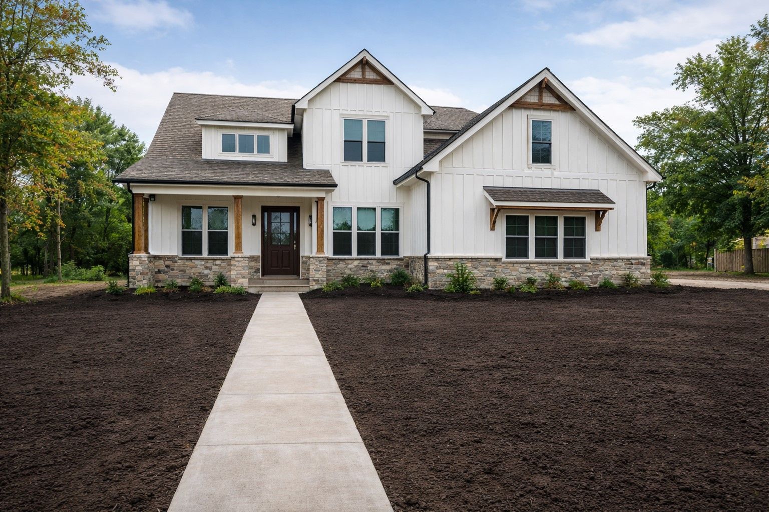 White farmhouse with stone accents and a concrete walkway.