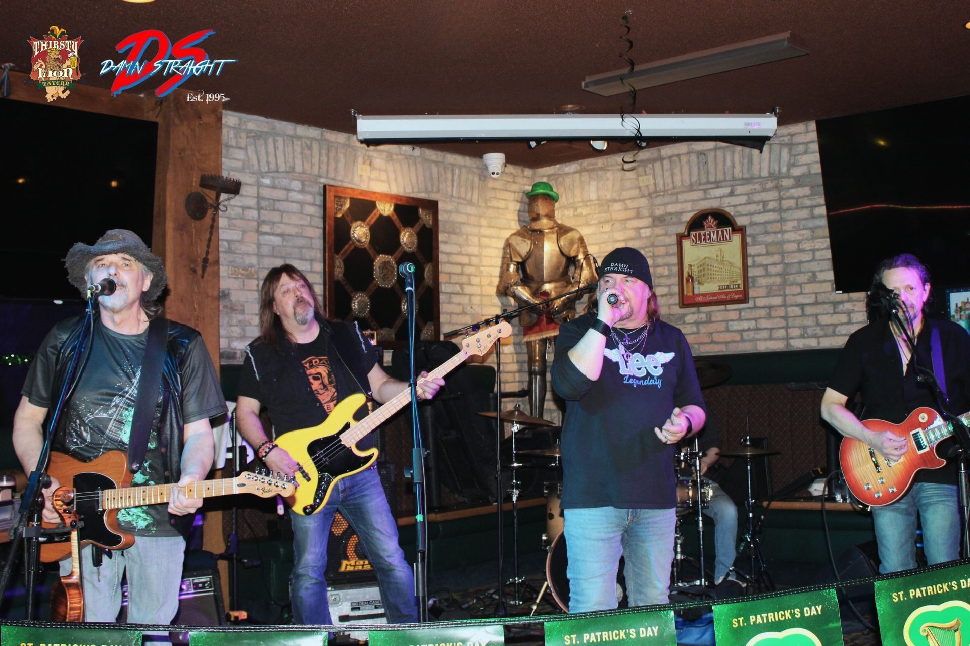 A band performs in a whimsical venue. Two guitarists and a singer. A person seated listens.