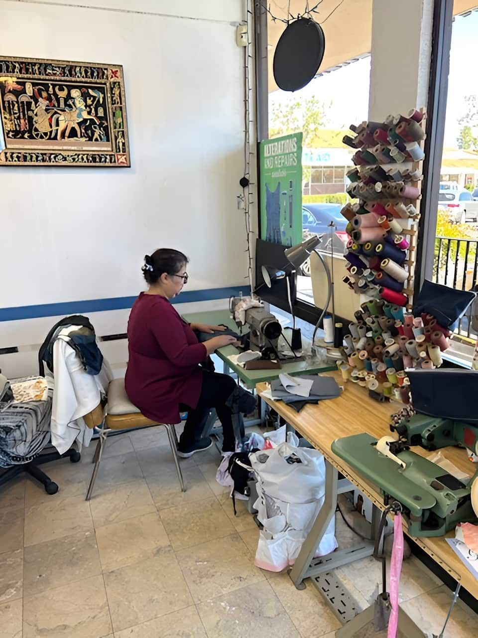 Woman sews at a sewing machine in a tailor shop. 
