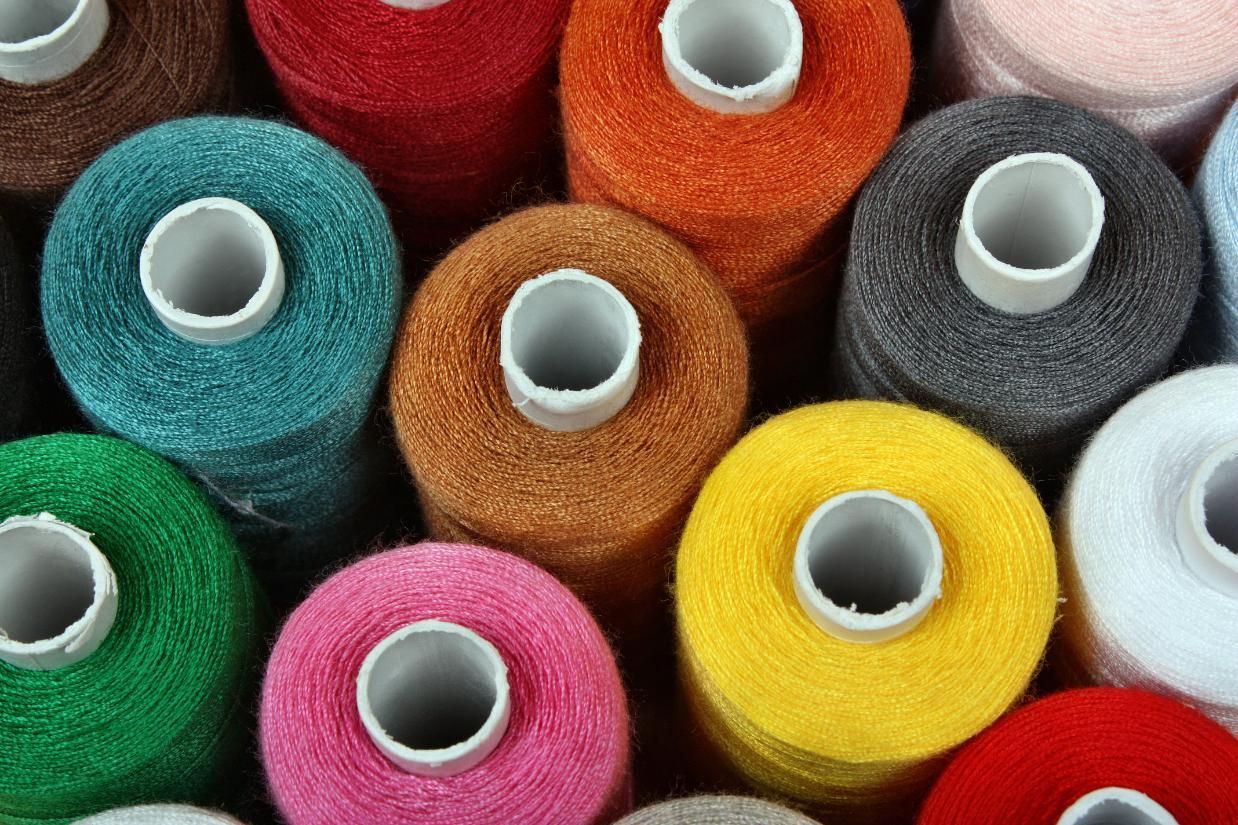 Spools of brightly colored thread in shades of green, orange, pink, yellow, and blue.