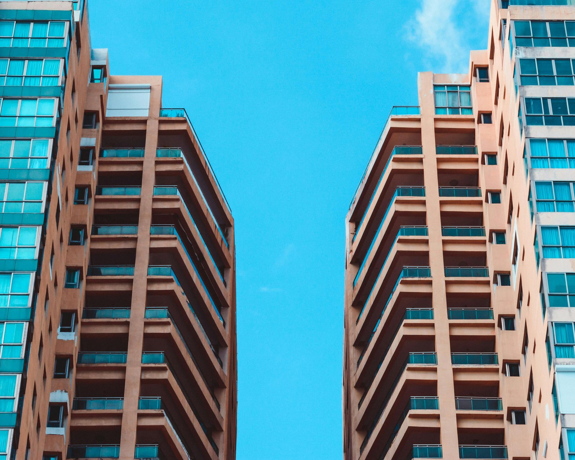 Tall buildings with balconies against a bright blue sky.