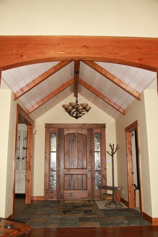 A hallway with a wooden door and a chandelier hanging from the ceiling