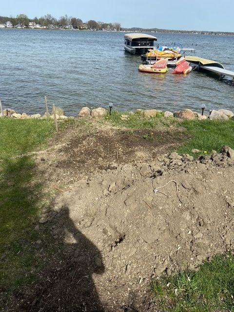 Rocky lakeshore with muddy bank, floating dock, and colorful kayaks on calm water