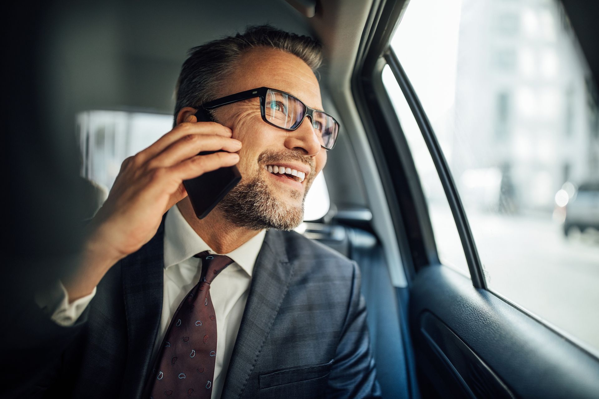 A Man Sitting In The Back Seat Of A Car Talking On A Cell Phone — Pittsfield, MA — Black Luxe Luxury Car