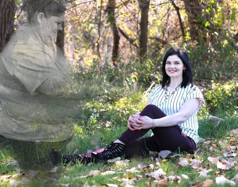 Woman sitting on grass in a sunlit park beside a translucent ghostly figure