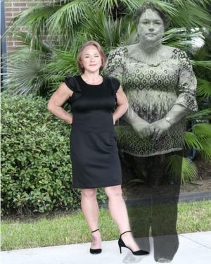 Woman in black dress posing beside a ghostly grayscale version of herself outdoors by palm plants