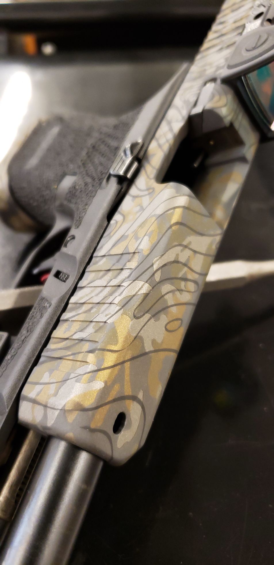 Close-up of a camouflaged handgun grip resting on a metal surface.