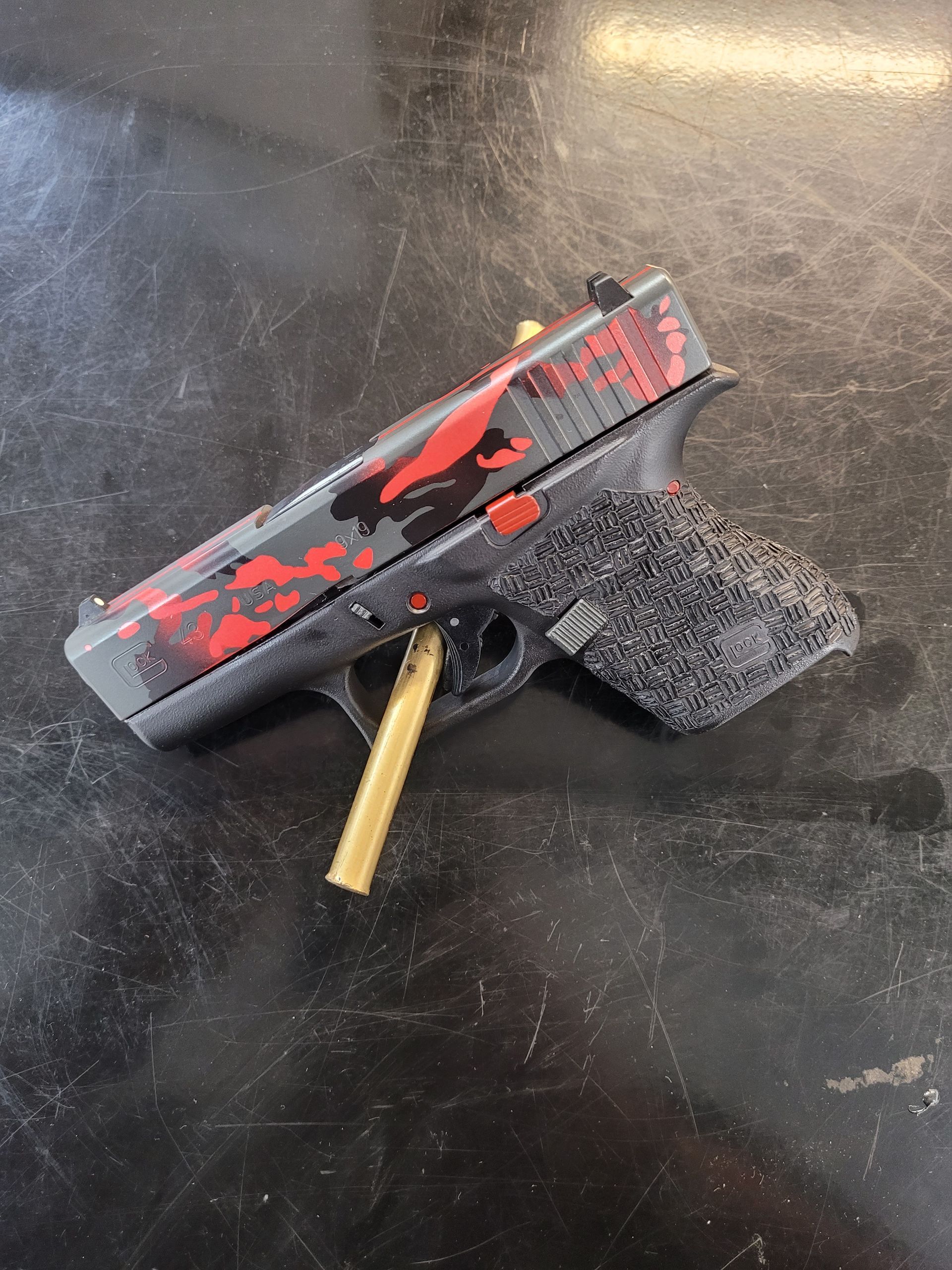 Black-and-red toy handgun with a gold barrel and foam grip on a dark tabletop