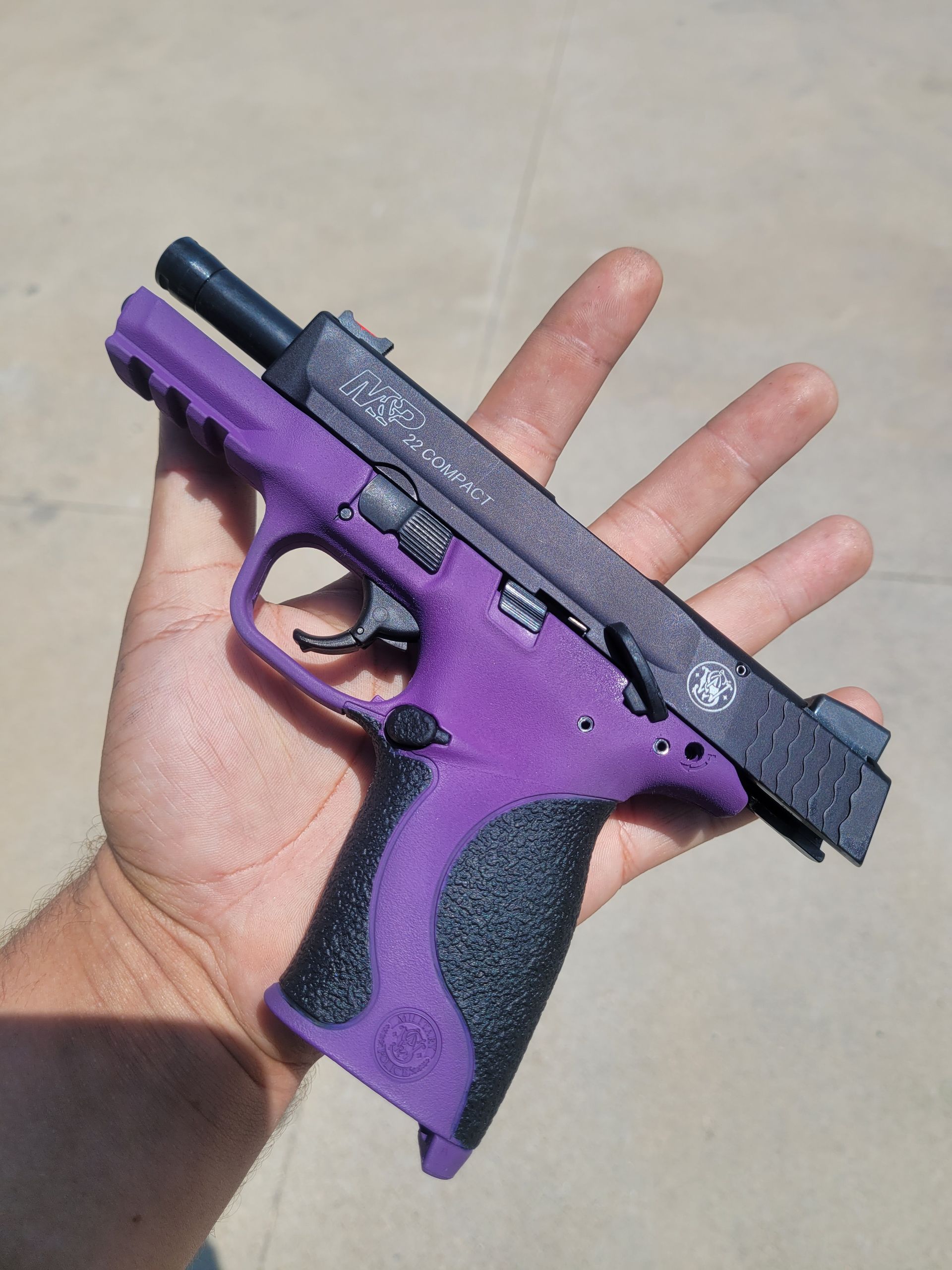 Purple-and-black toy handgun held in a hand against a light background