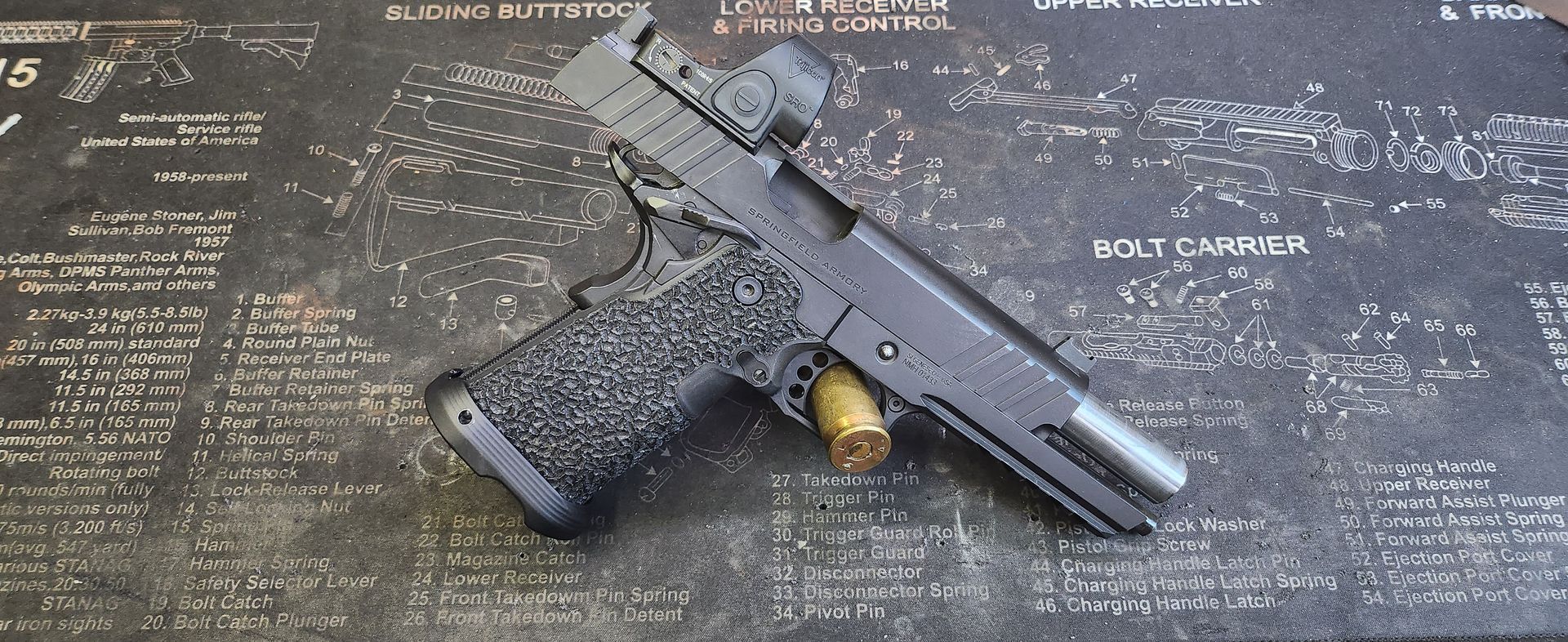 Black handgun with gold accents on a dark engraved surface