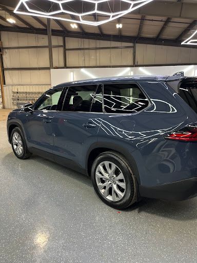 Blue-gray Toyota Highlander SUV with window tint installation at a detailing shop