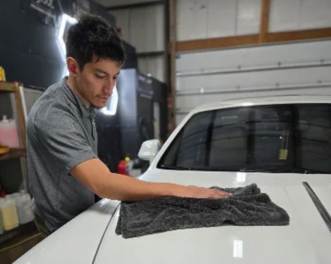 Installer applying ceramic coating to a white vehicle at CM3 Detailing Studio & Ceramic Coating in Elgin, IL
