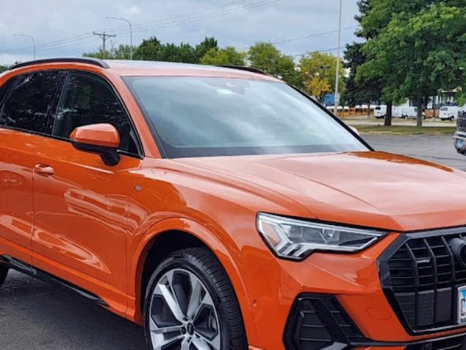 Orange Audi Q3 parked outdoors with a clean window tint on all side windows