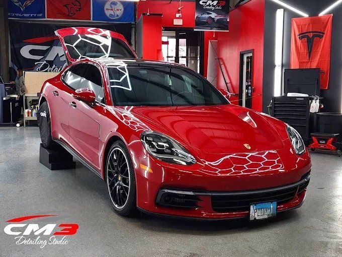 Red Porsche Panamera inside a detail shop with a glossy ceramic coating finish