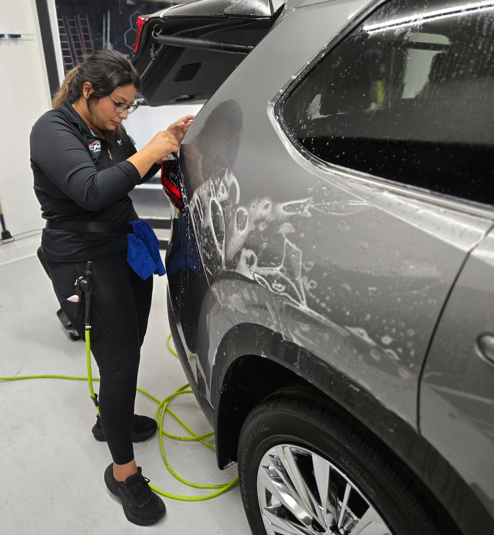 Professional installer applying clear bra paint protection film to a vehicle's rear quarter panel