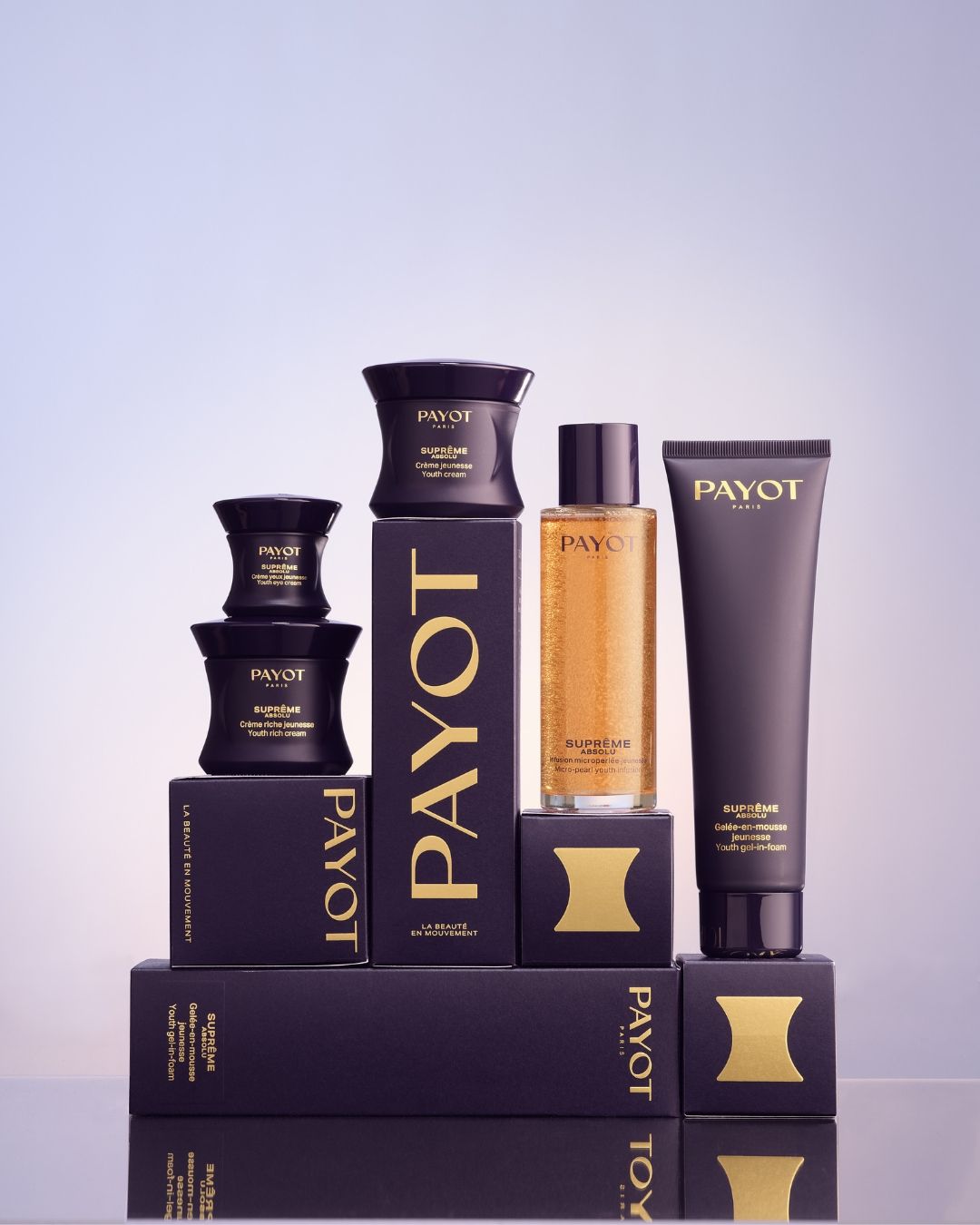 Payot-Hautpflegeprodukte in schwarzer, goldener und violetter Verpackung auf lavendelfarbenem Hintergrund