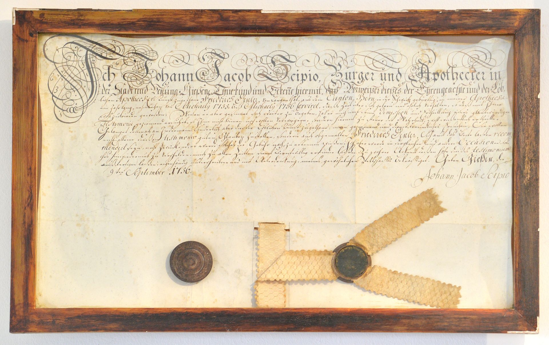 Gerahmtes antikes Zertifikat mit verblasster Schrift und zwei Wachssiegeln auf Pergament.
