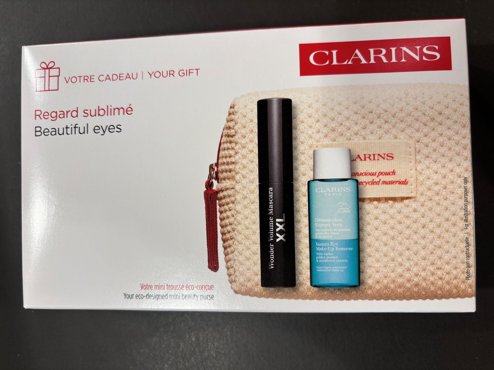 Clarins Beauty-Set mit beiger Clutch, schwarzer Mascara und blauer Hautpflegeflasche