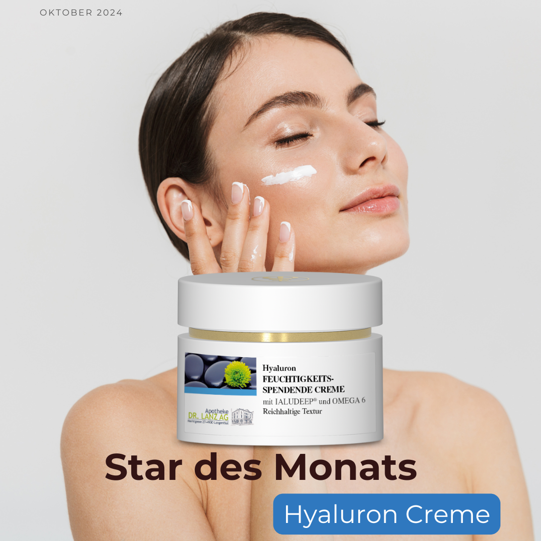 Frau trägt weisse Creme aus einem Tiegel mit der Aufschrift „Star des Monats Hyaluron Creme“ auf hellen Hintergrund auf.