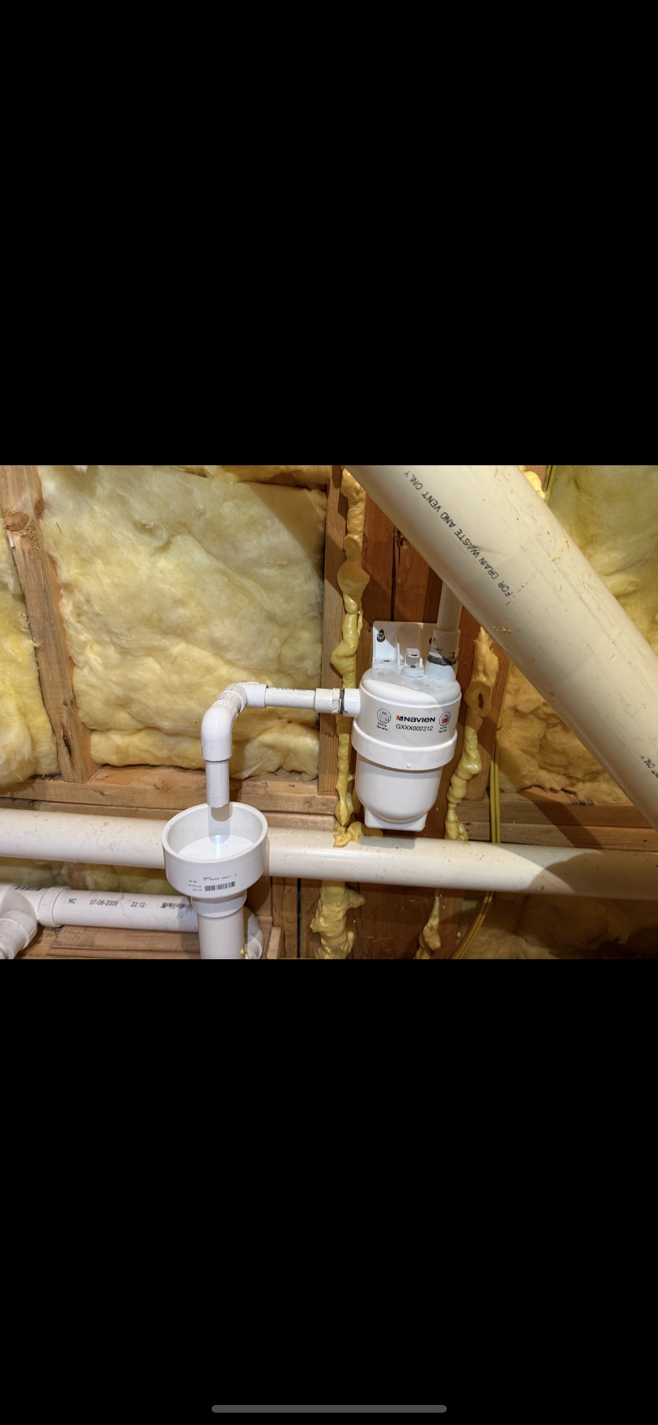 White PVC pipes and water valve system in a basement setting.
