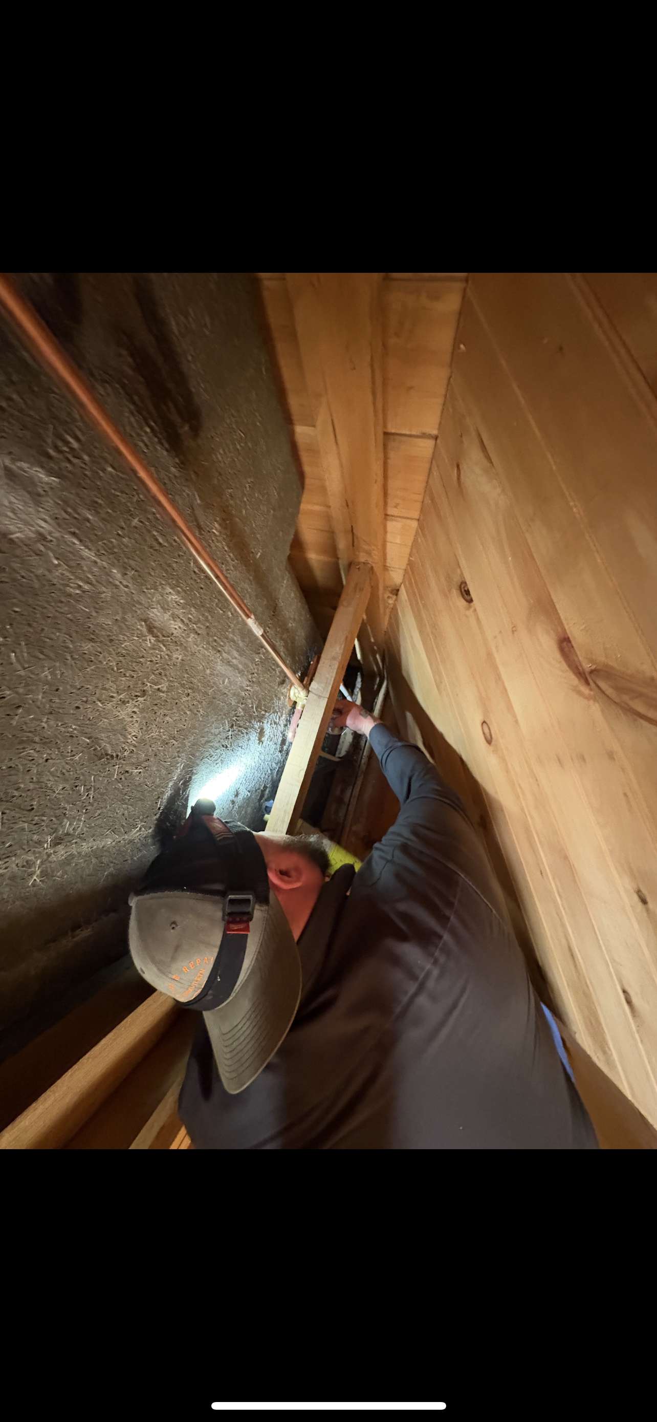 Person inside a confined space, using a saw to cut wood.