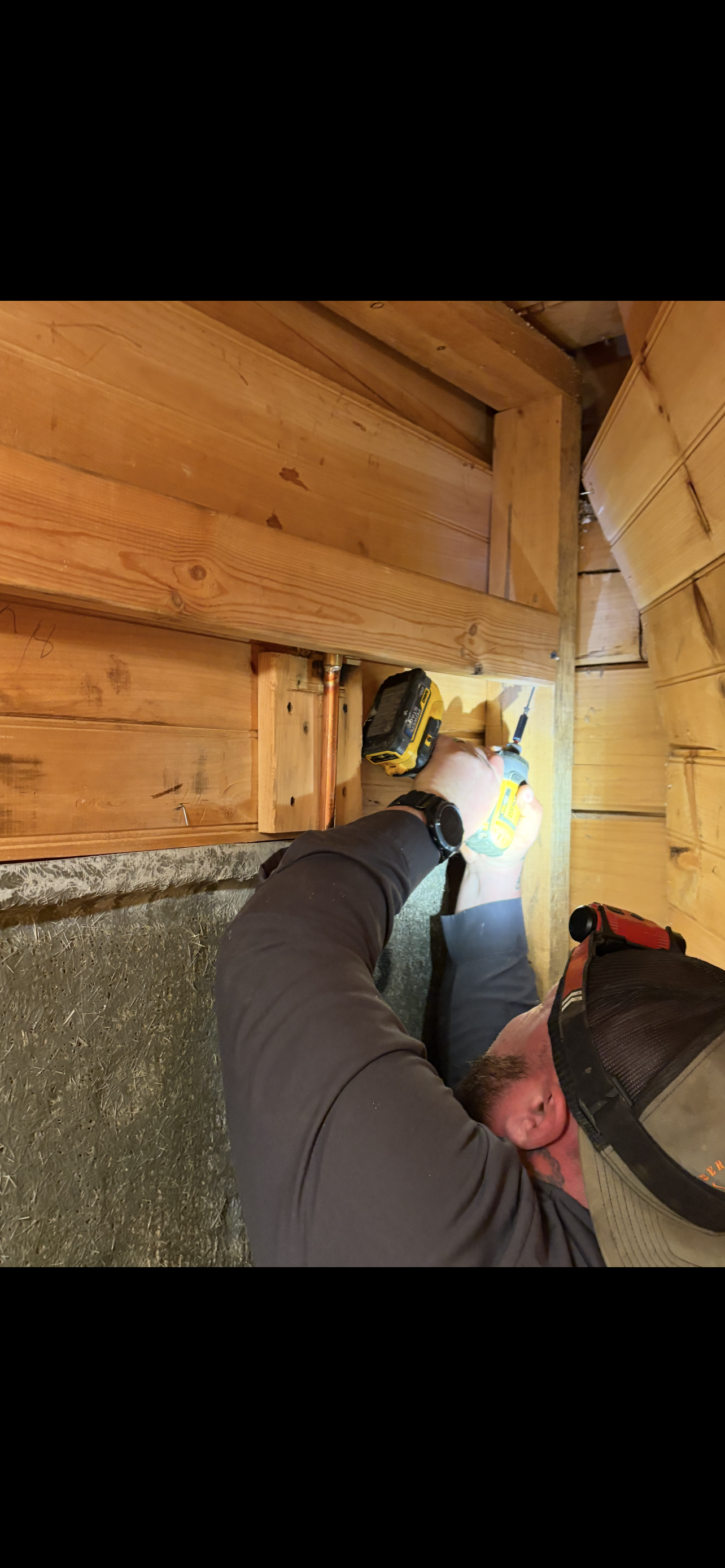 Person working with tools on wood beams.