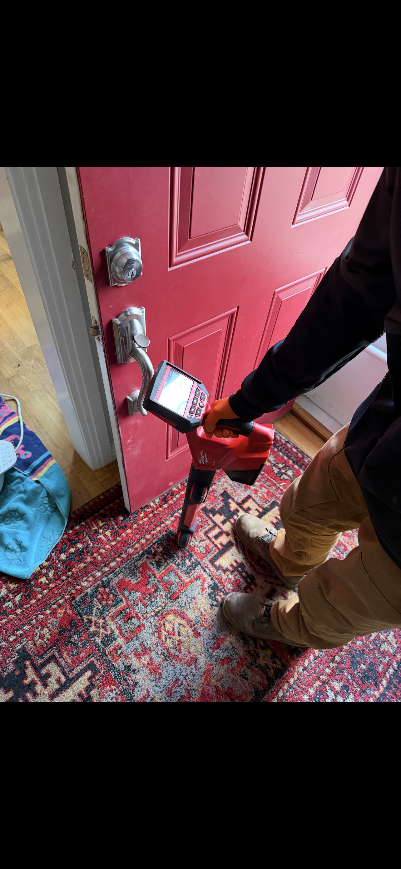 Person using a red power tool on a red door; inside a home.