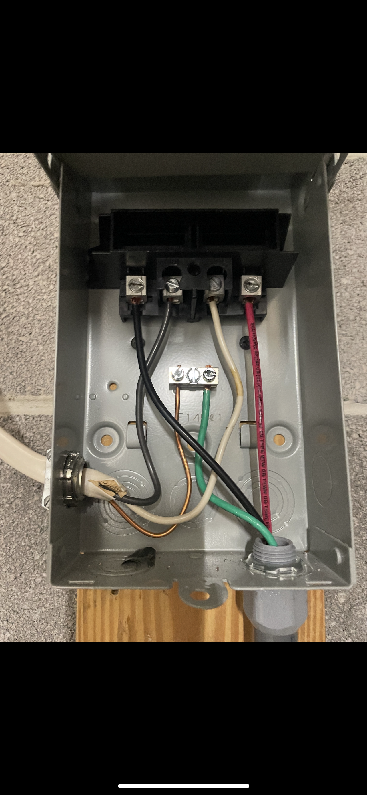 Open electrical junction box with connected wires of various colors.
