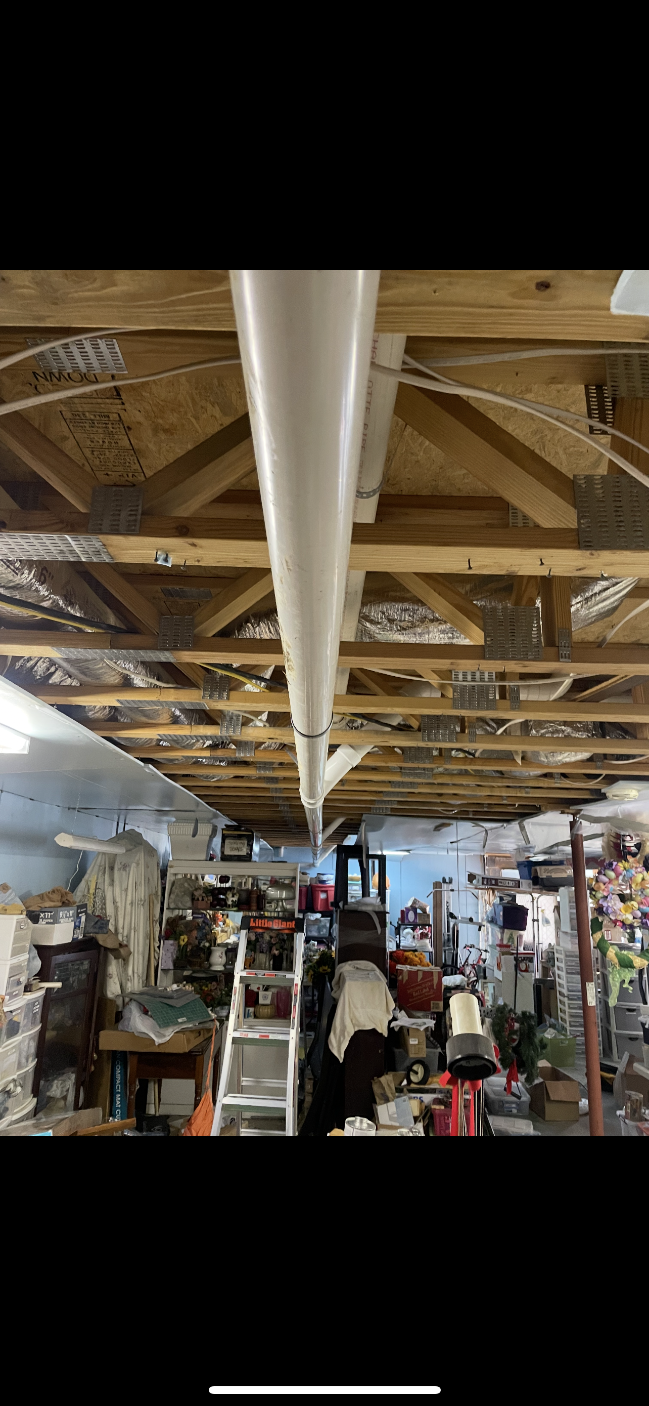 Low-angle shot of cluttered basement with white pipe running across the ceiling.