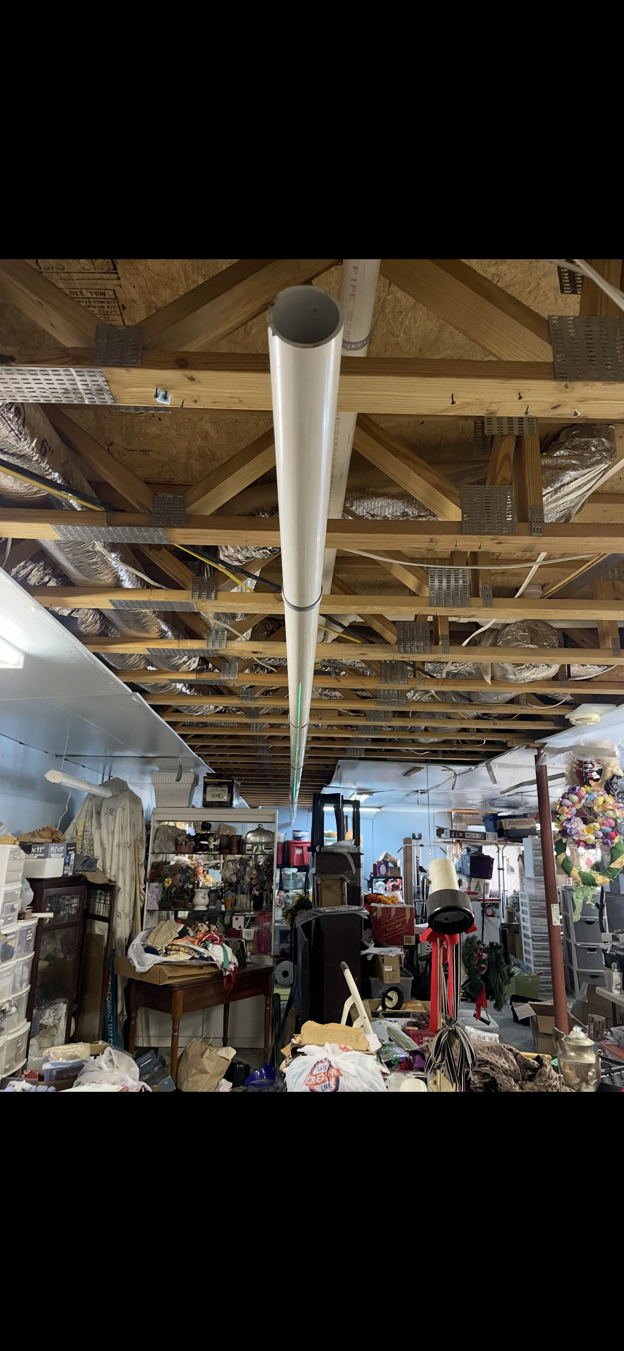 A cluttered, messy interior with a white pipe running along the ceiling.