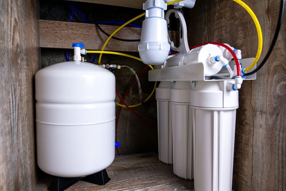 Reverse osmosis water filtration system with a storage tank inside a cabinet.