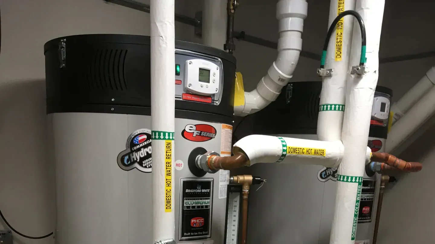 Two water heaters with white and copper pipes.
