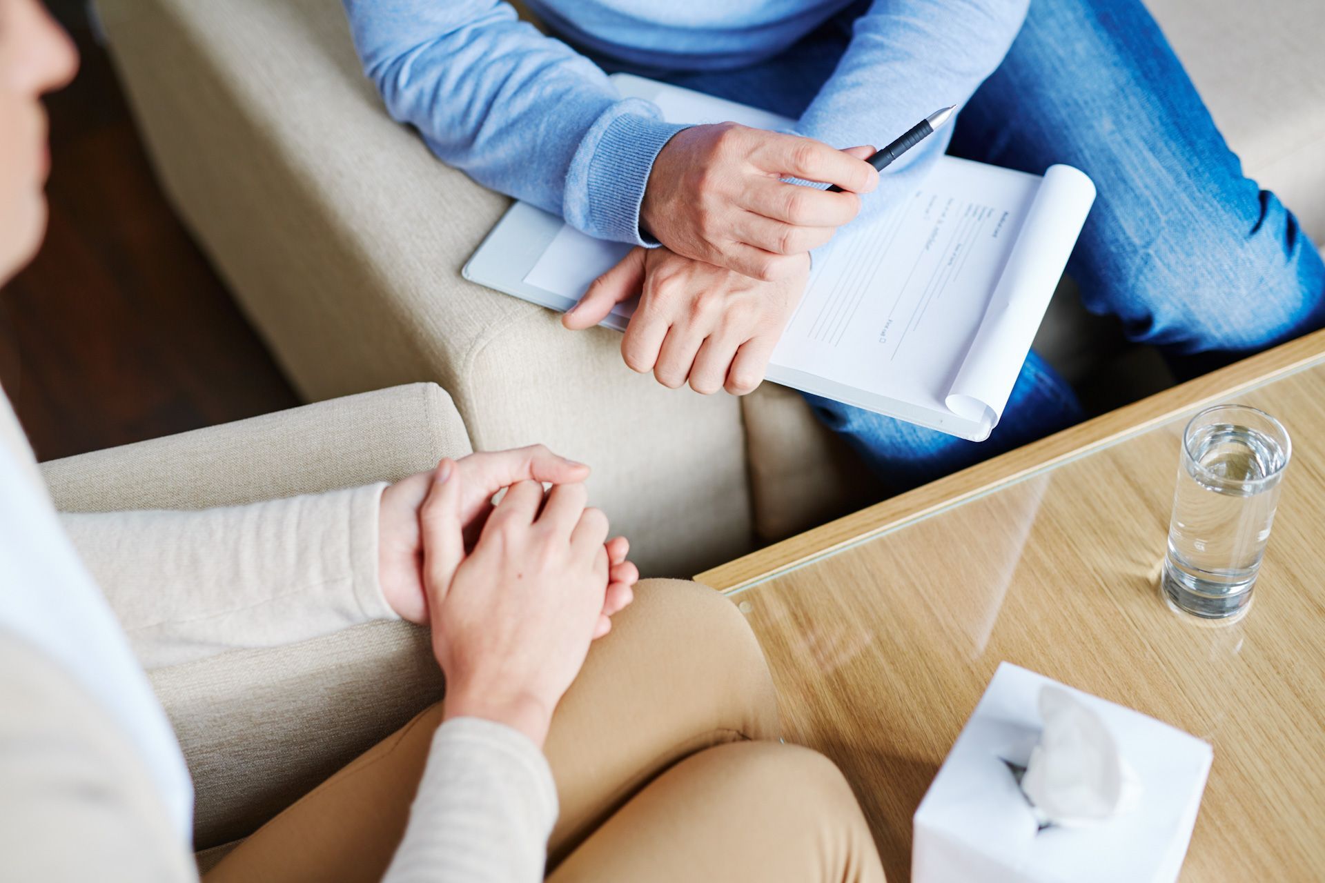 A woman is holding her hands and a man holding a clipboard