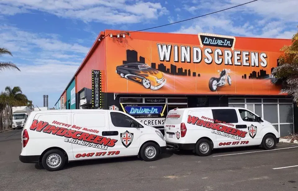 Two White Drive-In Windscreens Vans Parked Outside a Building — Hervey Bay Mobile Windscreens in Pialba, QLD