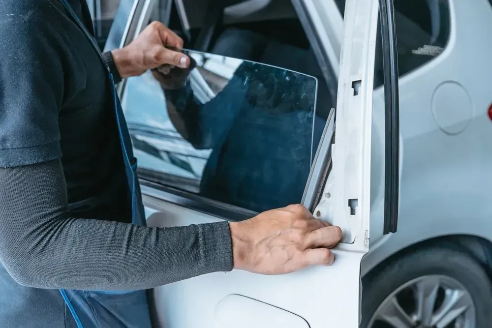 Person installing tinted film on a car window. — Hervey Bay Mobile Windscreens in Pialba, QLD