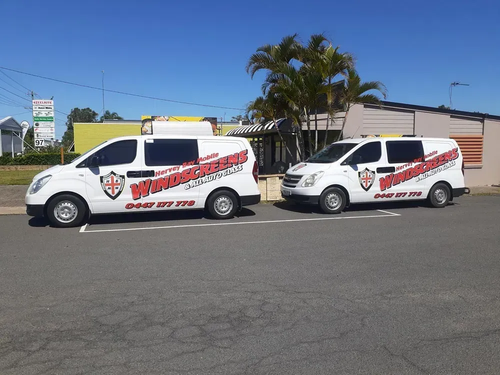 Two White Vans with Business Logos Parked on Pavement — Hervey Bay Mobile Windscreens in Pialba, QLD