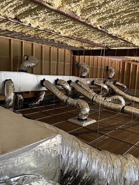 HVAC ductwork in an attic, with insulation and silver tubing.