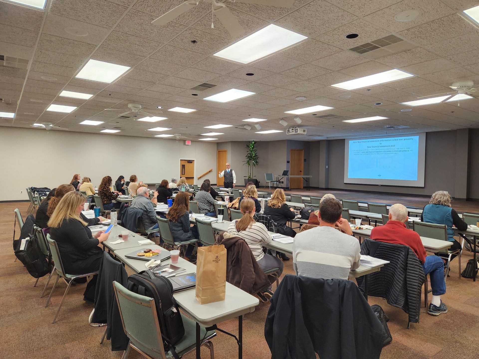 A large group of people are sitting at tables in a conference room.