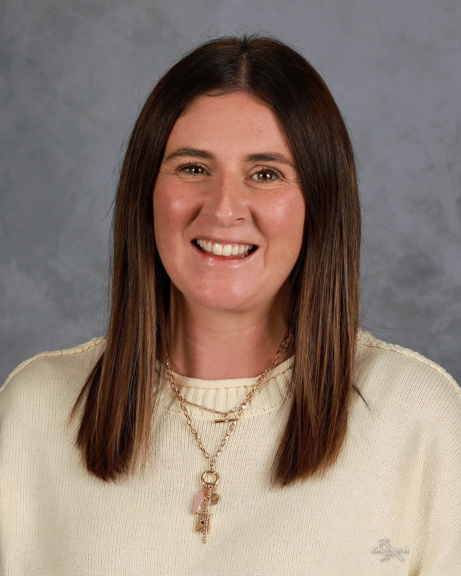 A woman in a pink shirt is smiling for the camera.