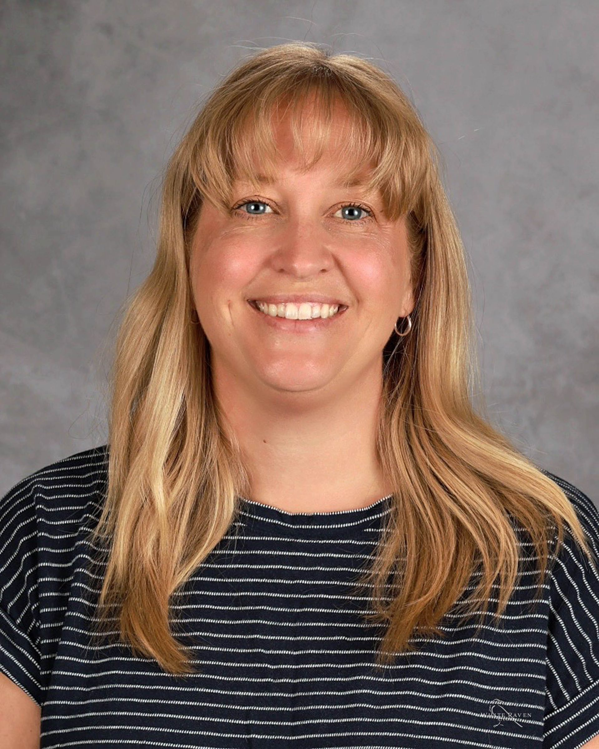 A woman with blonde hair and blue eyes is smiling for a picture.
