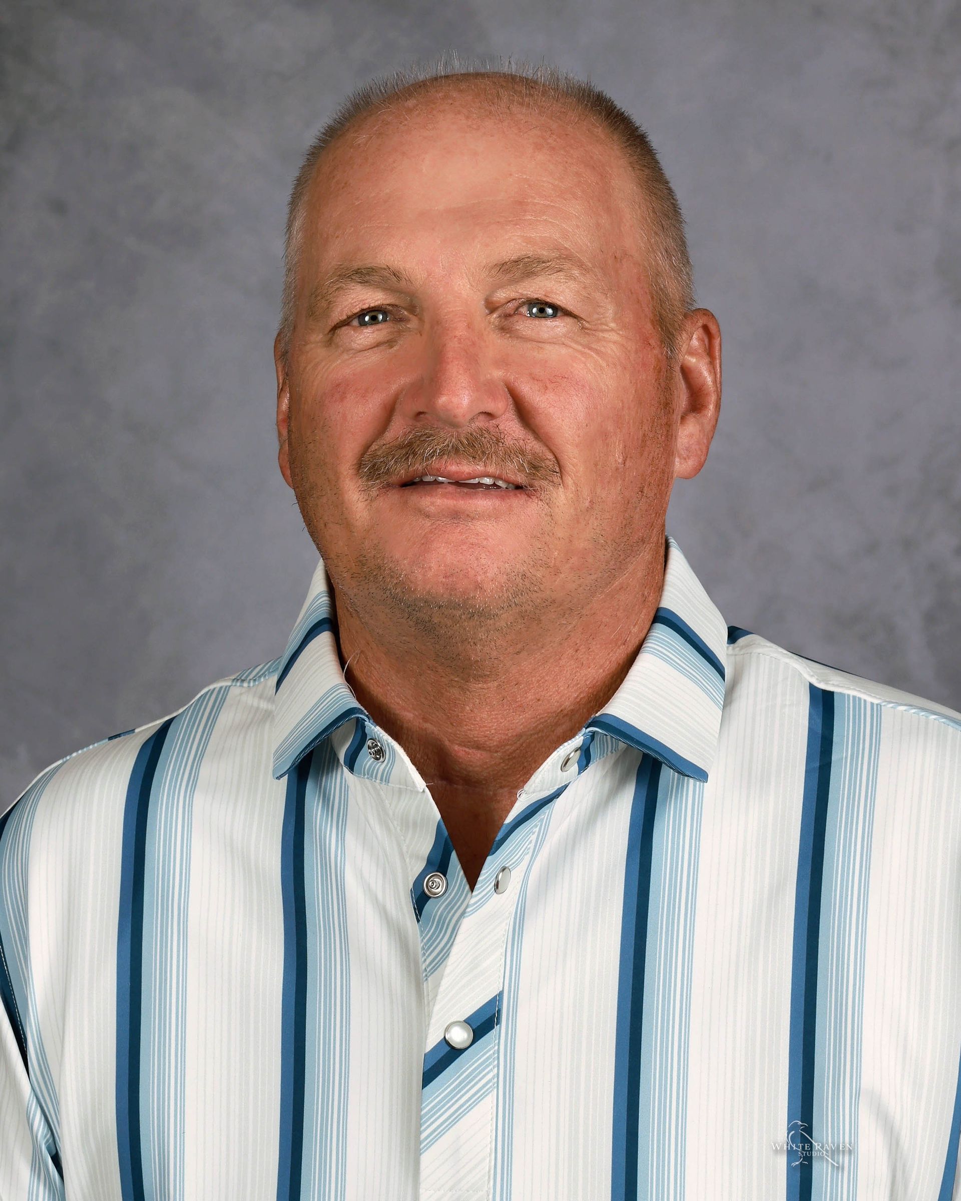 A man with a mustache is wearing a red and black striped shirt.