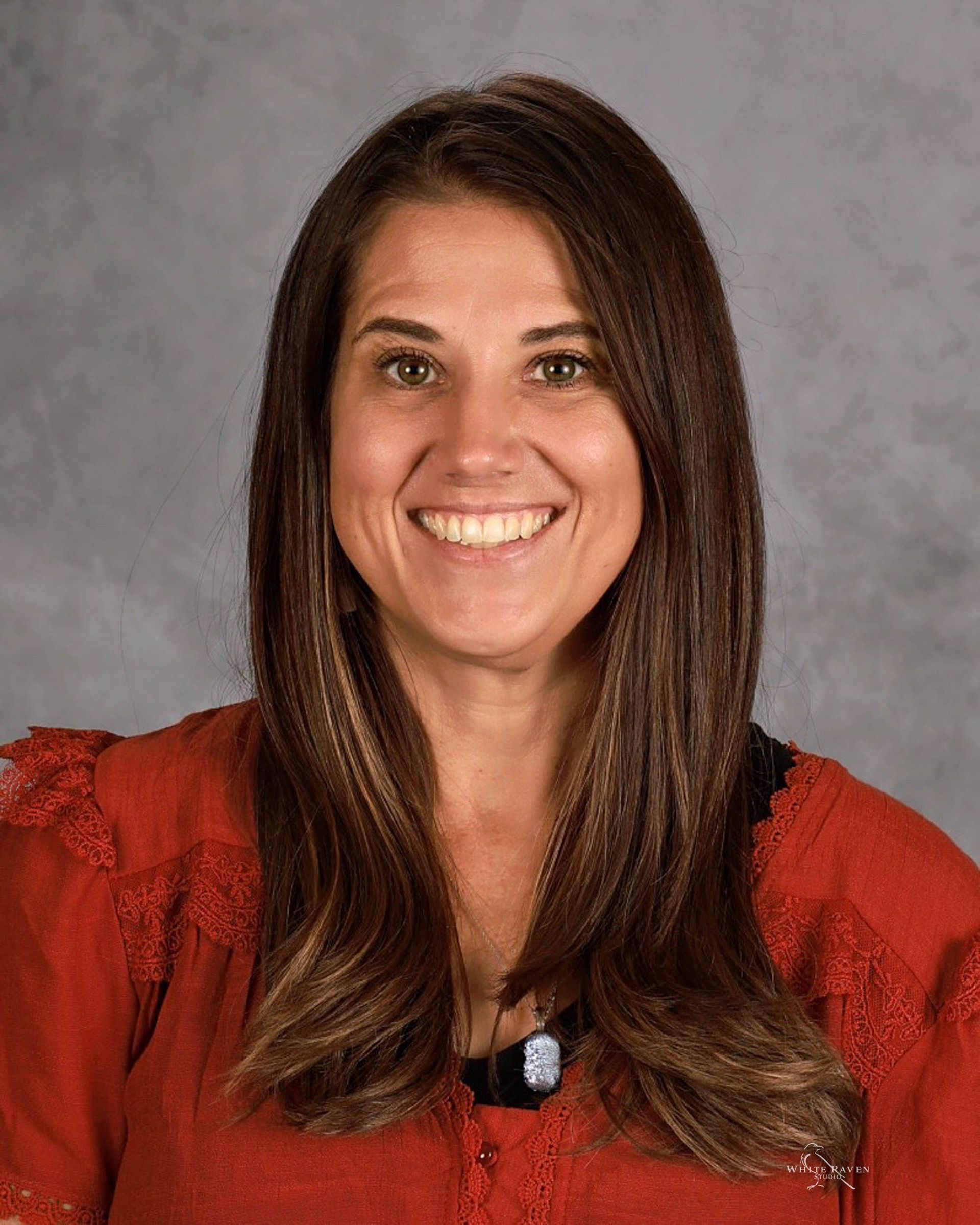 A woman in a pink sweater is smiling for the camera.
