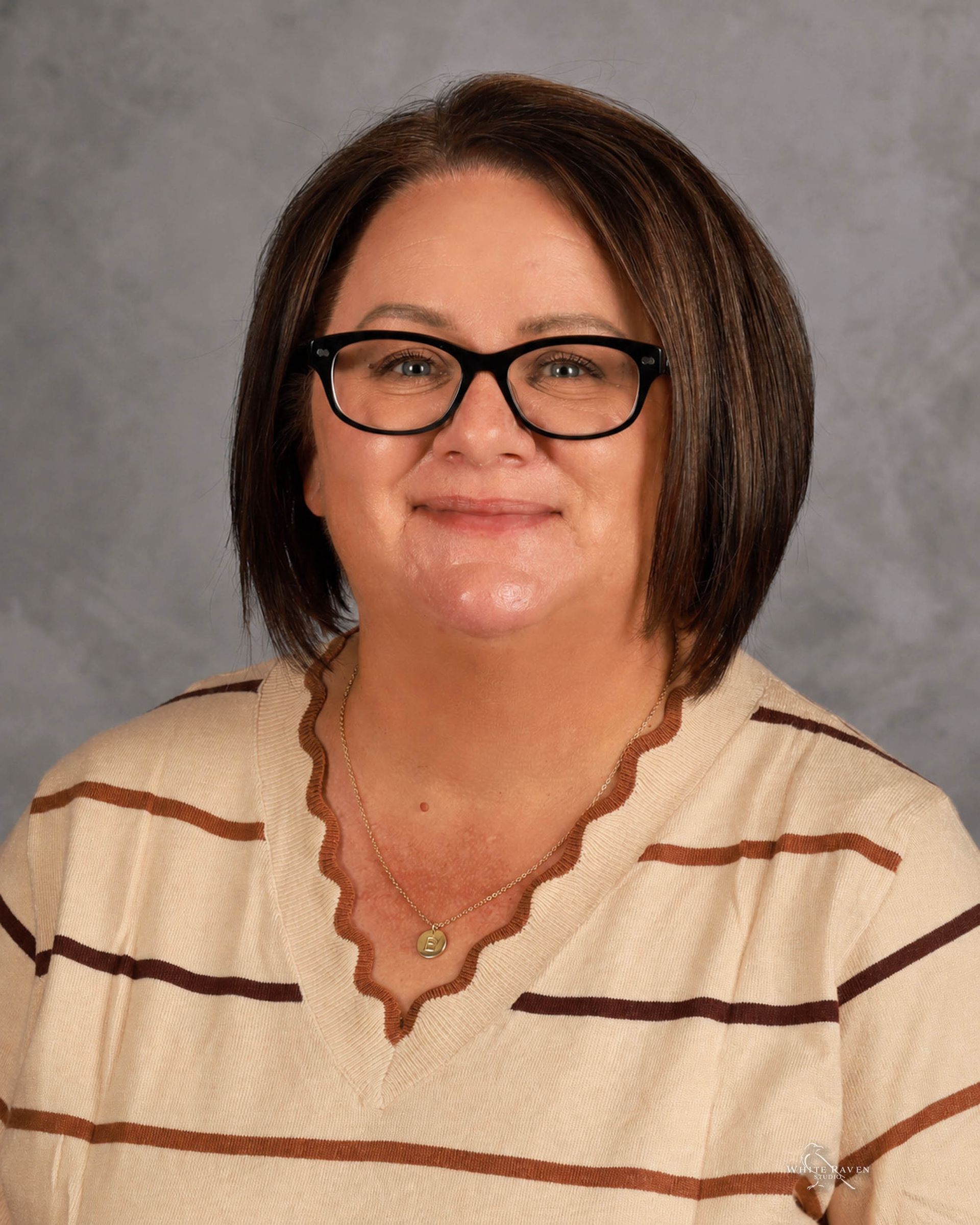 A woman wearing glasses and a blue sweater is smiling for the camera.